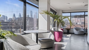 A modern interior with a city view, a round table, and seating areas. - Boutique Studio with Rooftop View and Gym (Philadelphia)