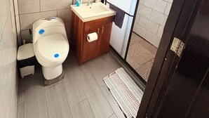 Et badeværelse med toilet, håndvask og bruseområde.