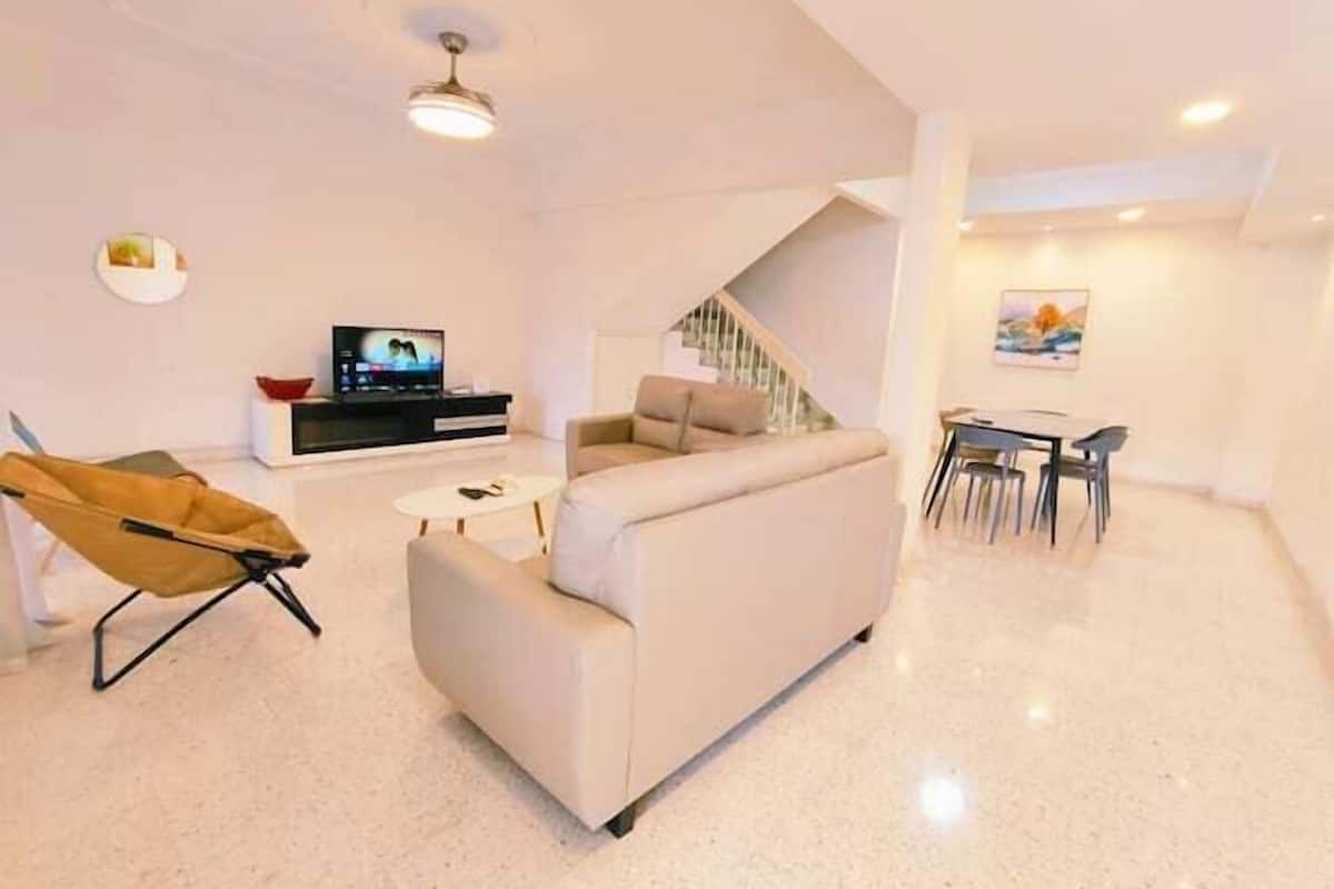 Una sala de estar moderna con un sofá, un televisor, una mesa de comedor con sillas y una escalera.