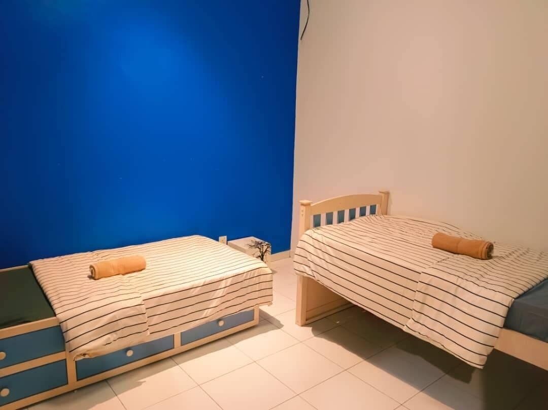 A room with two beds, each with striped bedding and a rolled towel.