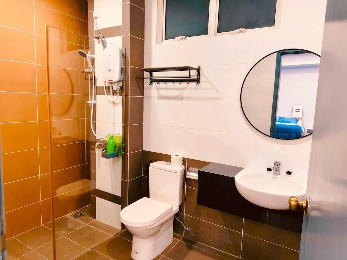 Un baño con ducha, inodoro, lavamanos y espejo.