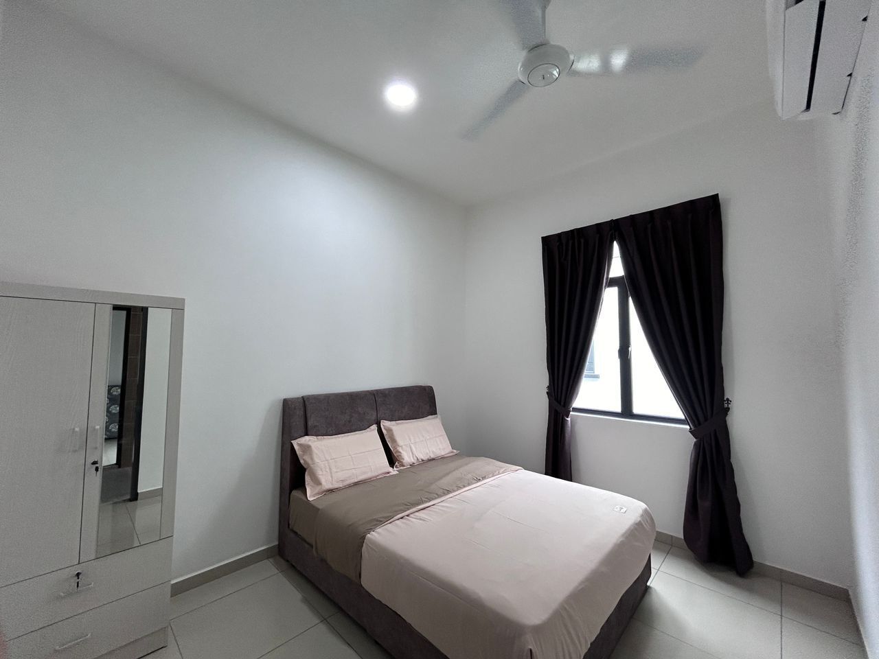 A bedroom with a bed, a wardrobe, a ceiling fan, and a window with curtains.