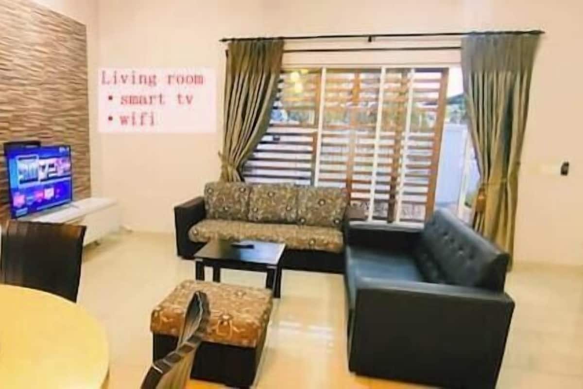 Una sala de estar con sofá, mesa de centro, televisor y un cartel que indica servicios como TV inteligente y wifi.