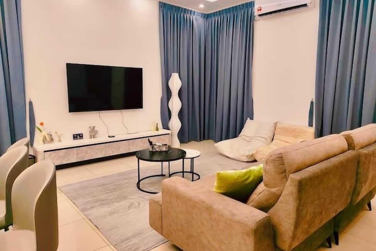 Una sala de estar moderna con televisor de pantalla plana, un sofá, una mesa de centro y una zona de comedor con sillas.