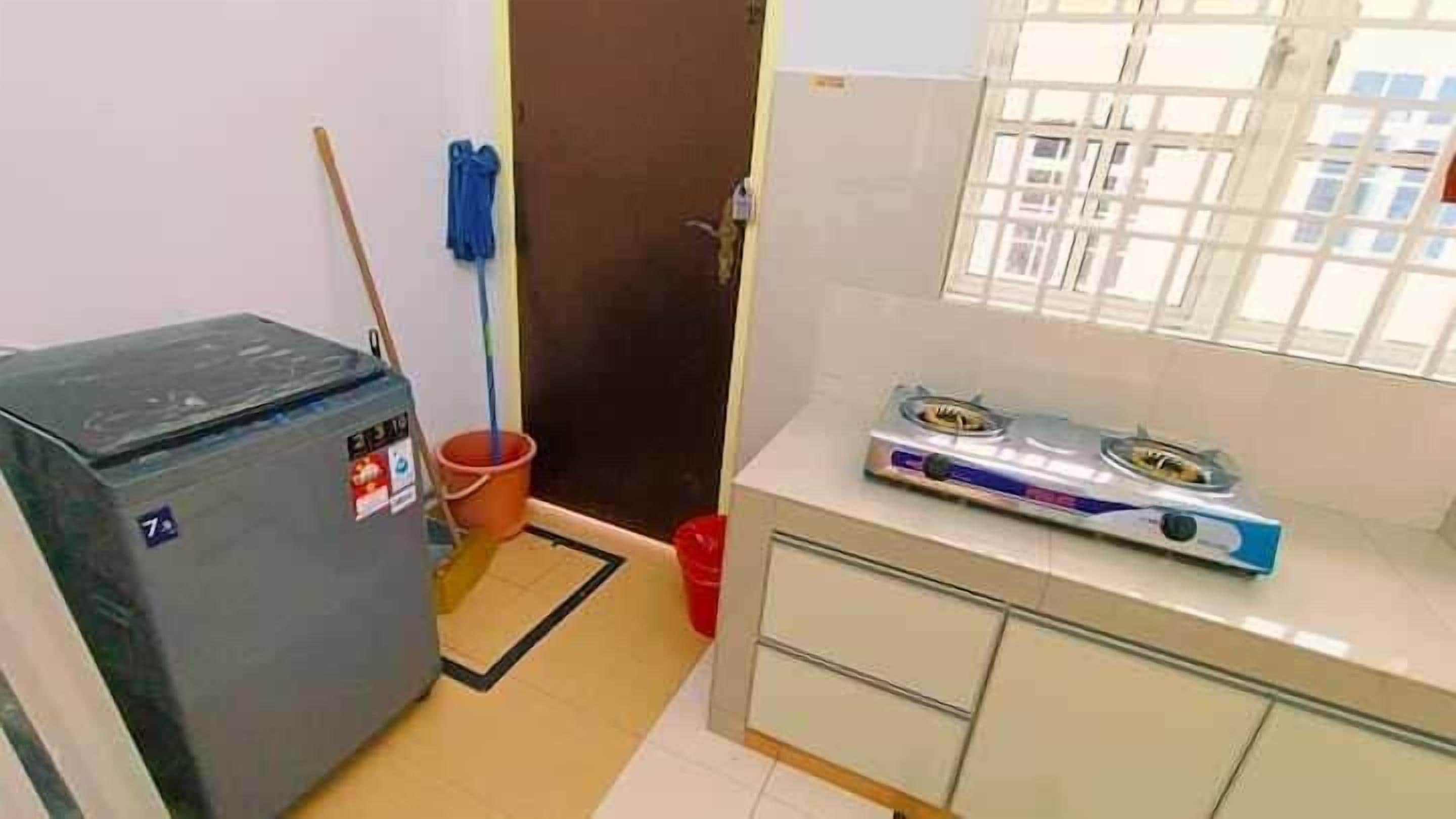A compact kitchen with a gas stove, a washing machine, and a mop.