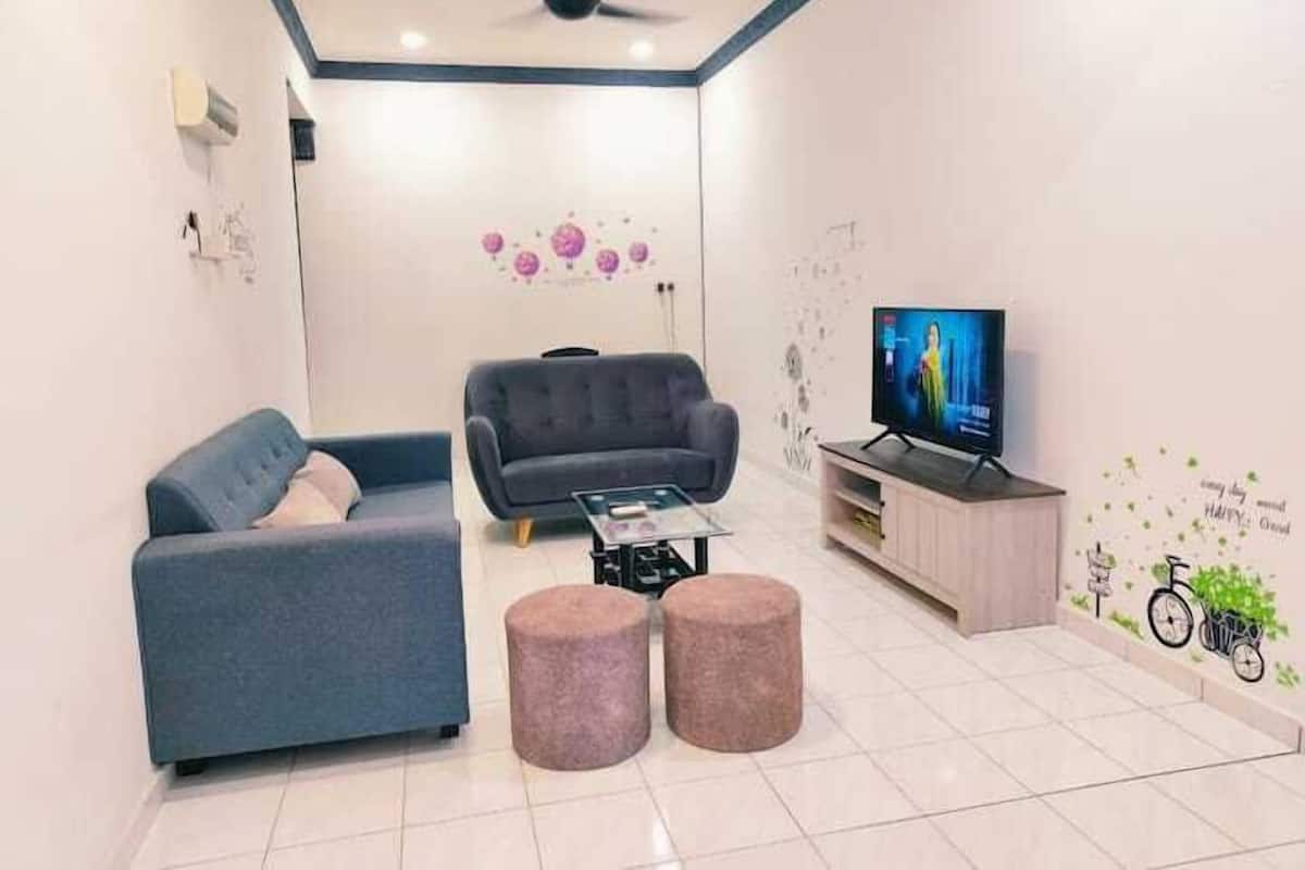 Una sala de estar moderna con un sofá, otomanas, una mesa de centro, un televisor y un ventilador de techo.