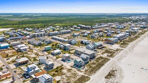Vista aérea de una zona residencial costera con varios edificios, incluyendo casas y posiblemente un hotel, a lo largo de la playa.