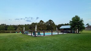 A pool area with a wooden deck, chairs, and a statue.