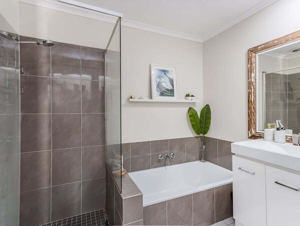 A modern bathroom with a shower, bathtub, and vanity.