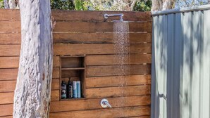 Eine Duschkabine aus Holz mit integriertem Ablagebereich für Toilettenartikel.