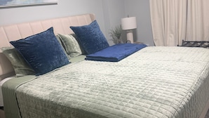 A bedroom with a bed, pillows, a lamp, and a painting on the wall. - Charming 2-bedroom townhome in Winter Springs. (Winter Springs)