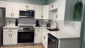 A modern kitchen with white cabinets, stainless steel appliances, and a small herb garden on the wall. - Charming 2-bedroom townhome in Winter Springs. (Winter Springs)