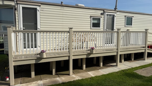 A mobile home with a porch, two windows, and a chimney.