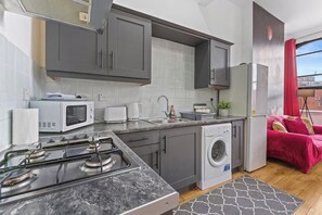 A compact kitchen with a gas stove, microwave, toaster, and washing machine.