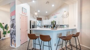 A modern kitchen with a central island, bar stools, and pendant lighting. - Welcome to the Coco Cabana! Located in Estrella Mountain Ranch in Goodyear, AZ! (Goodyear)