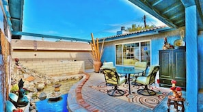 A patio with a table and chairs, a small pool, and a decorative fountain.