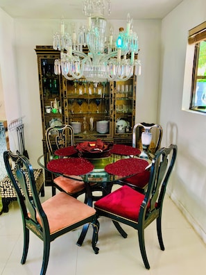 A dining area with a round table, chairs, and a chandelier.