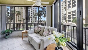 A balcony with a ceiling fan, a sofa, a small table, and a potted plant.