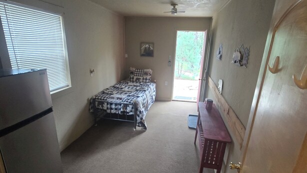 A bedroom with a bed, a ceiling fan, a window, and a door. - Hunter's Shack - Bear Cabin (Mayhill)