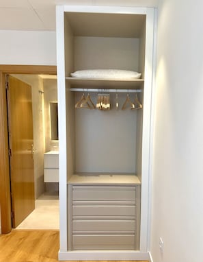 A walk-in closet with a hanging rod, a padded shelf, and drawers.