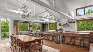 A spacious kitchen with a large island, wooden dining table, and bar stools. - THE ULTIMATE RURAL RETREAT Sleeps 13 situated in Berima Southern Highlands NSW (Berrima)