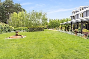 A well-maintained lawn, a fountain, and a building with a covered porch.