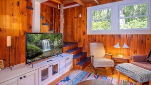A wooden interior with a TV, staircase, and seating area.