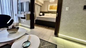 A hotel room with a bed, a desk, a chair, and a TV.