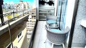 A balcony with wicker furniture, a view of the city, and a decorative wall piece.
