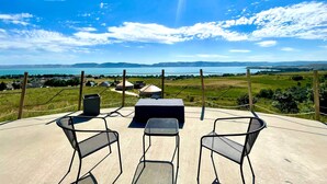 A terrace with outdoor seating, a view of a lake, and distant mountains. - The Black Bear Yurt: Rustic Hilltop Escape with Stunning Bear Lake Views – Sleeps 12! (Garden City)