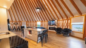 A spacious kitchen with a large island, wooden flooring, and a high ceiling with exposed beams. - The Black Bear Yurt: Rustic Hilltop Escape with Stunning Bear Lake Views – Sleeps 12! (Garden City)