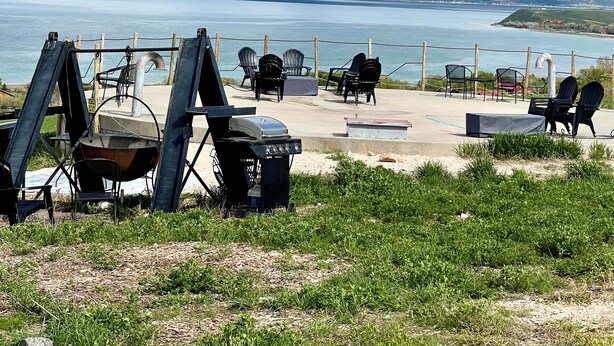 An outdoor seating area with chairs and tables overlooking a body of water and distant hills. - The Black Bear Yurt: Rustic Hilltop Escape with Stunning Bear Lake Views – Sleeps 12! (Garden City)