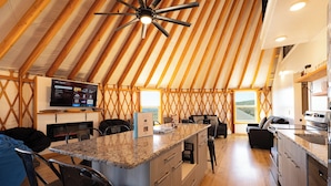 Cocina y sala de estar modernos de concepto abierto, con techo de madera, electrodomésticos integrados y una isla grande.