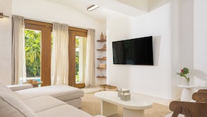 A modern living room with a sofa, a coffee table, and a TV mounted on the wall. - Roga Villa- Wellness, Tropical, Pool, Sauna, Ice Bath, 5 min to Encuentro beach (Encuentro Ocean Caberete)