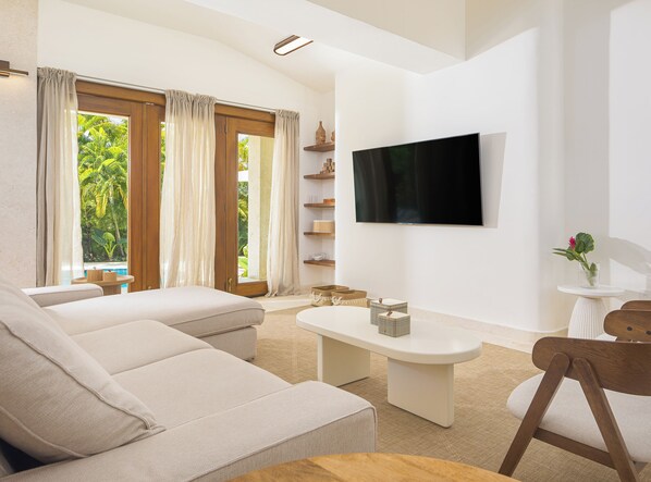 A modern living room with a sofa, a coffee table, and a TV mounted on the wall.
