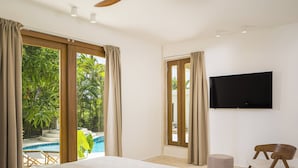 A bedroom with a large bed, a TV mounted on the wall, and a view of a swimming pool. - Roga Villa- Wellness, Tropical, Pool, Sauna, Ice Bath, 5 min to Encuentro beach (Encuentro Ocean Caberete)