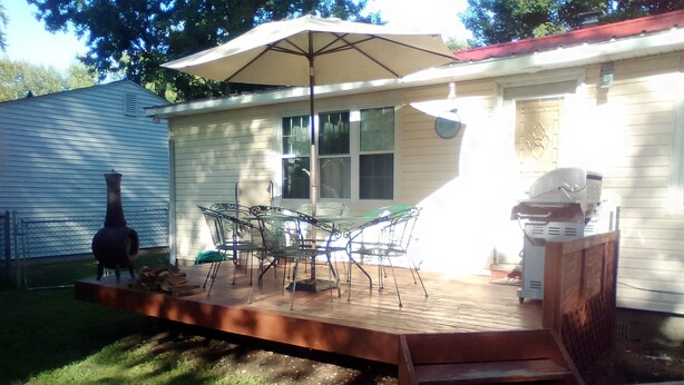 Une terrasse à l’arrière de la maison, avec une table et des chaises, un barbecue et un fumoir.