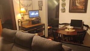 Un salon comprenant un canapé, un téléviseur, une table à manger avec des chaises et une cheminée.
