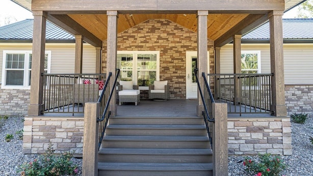 A covered porch with stone walls, a staircase, and outdoor seating. - Spacious Lodge w/ Fire Pit & Hot Tub (Wallingford)
