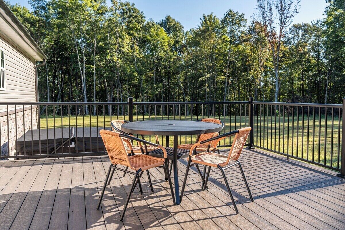 Una terraza con una mesa redonda y cuatro sillas, rodeada por una barandilla de metal.