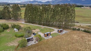 A remote cabin area with two cabins, a small greenhouse, and a dirt path. - Whitestone Retreat 1 by Tiny Away (Hillside)