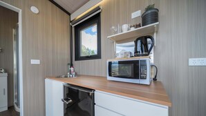 A compact kitchen with a microwave, sink, and storage cabinets. - Whitestone Retreat 1 by Tiny Away (Hillside)