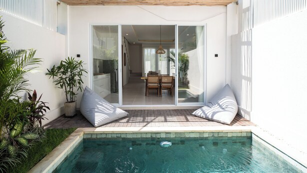 Une maison moderne dotée d’une piscine, de portes-fenêtres coulissantes donnant sur un coin repas et d’une pergola surplombant la terrasse.