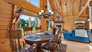 A wooden interior with a round dining table, chairs, and a blue sofa. - Mountain Escape on 6 acres w Hot Tub & Privacy (Baker)