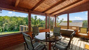 A wooden deck with a round table and chairs, large windows offering a view of greenery and hills. - Mountain Escape on 6 acres w Hot Tub & Privacy (Baker)