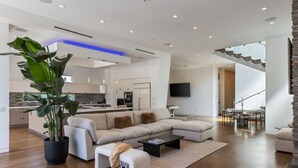 A modern living room with a sectional sofa, a coffee table, and a large potted plant. - West Hollywood Haven: Pool, Chef’s Kitchen & More (Los Angeles)