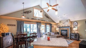 A spacious living area with a high ceiling, a fireplace, and a television. - Finley Lodge | 5 Mins to Attitash | Game Room (Bartlett)