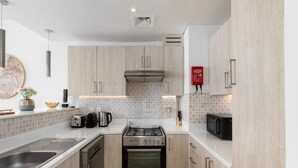 A modern kitchen with stainless steel appliances, wooden cabinets, and a tiled backsplash. - Elegant Palm Retreat w Iconic Sea Marina Vws (Dubai)