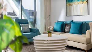 A modern living room with a sofa, a coffee table, and a painting on the wall. - Elegant Palm Retreat w Iconic Sea Marina Vws (Dubai)