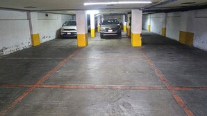 Autotalli, jossa on betonilattia, keltaiset pilarit ja katossa turvakamera.